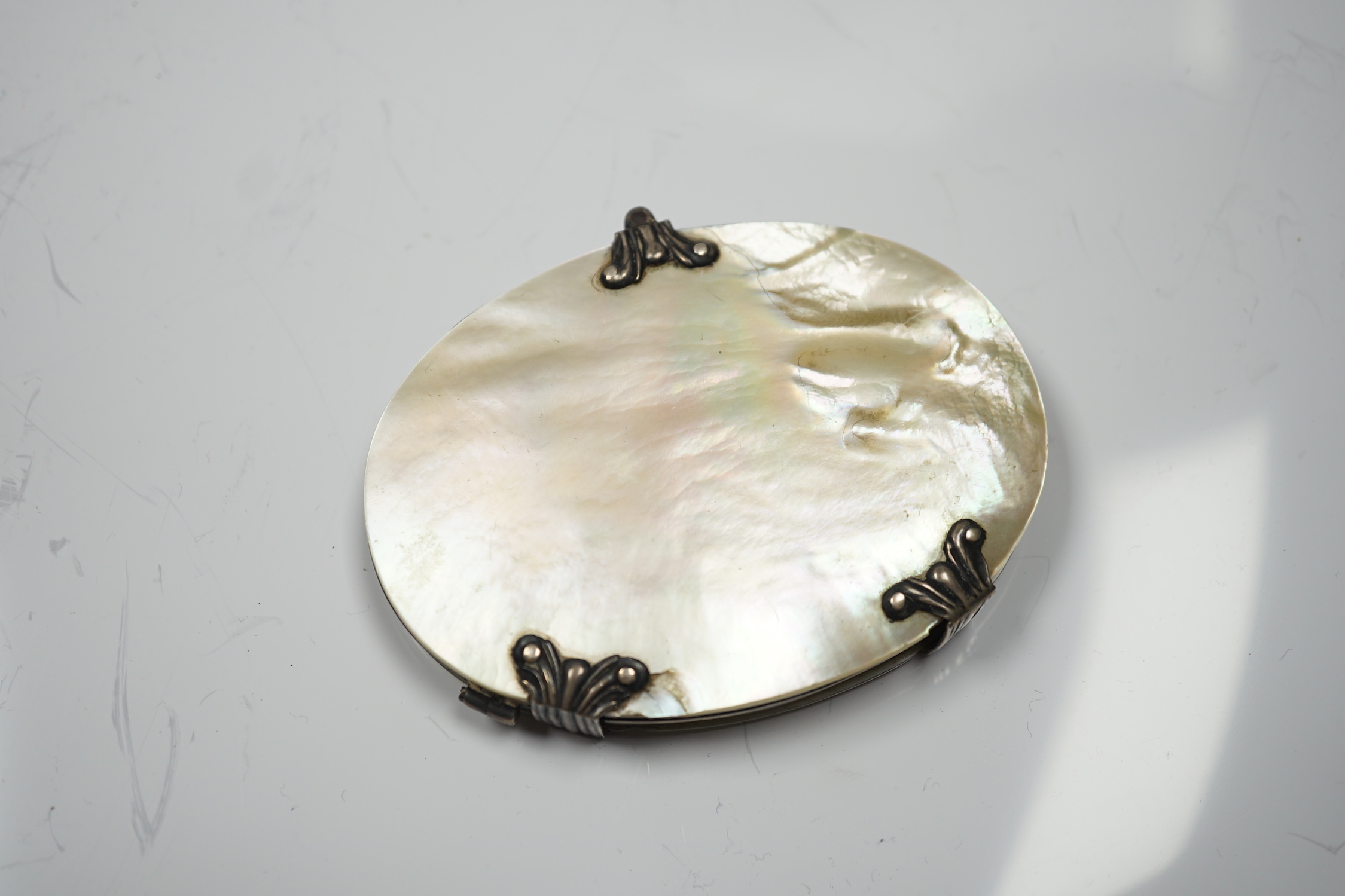 A 19th century white metal and mother of pearl mounted oval folding magnifying glass (a.f.), 90mm.
